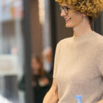 Profilaufnahme von Mirjam Stegherr in hellbraunem Pullover, mit Headset und Moderationskarten, lachend